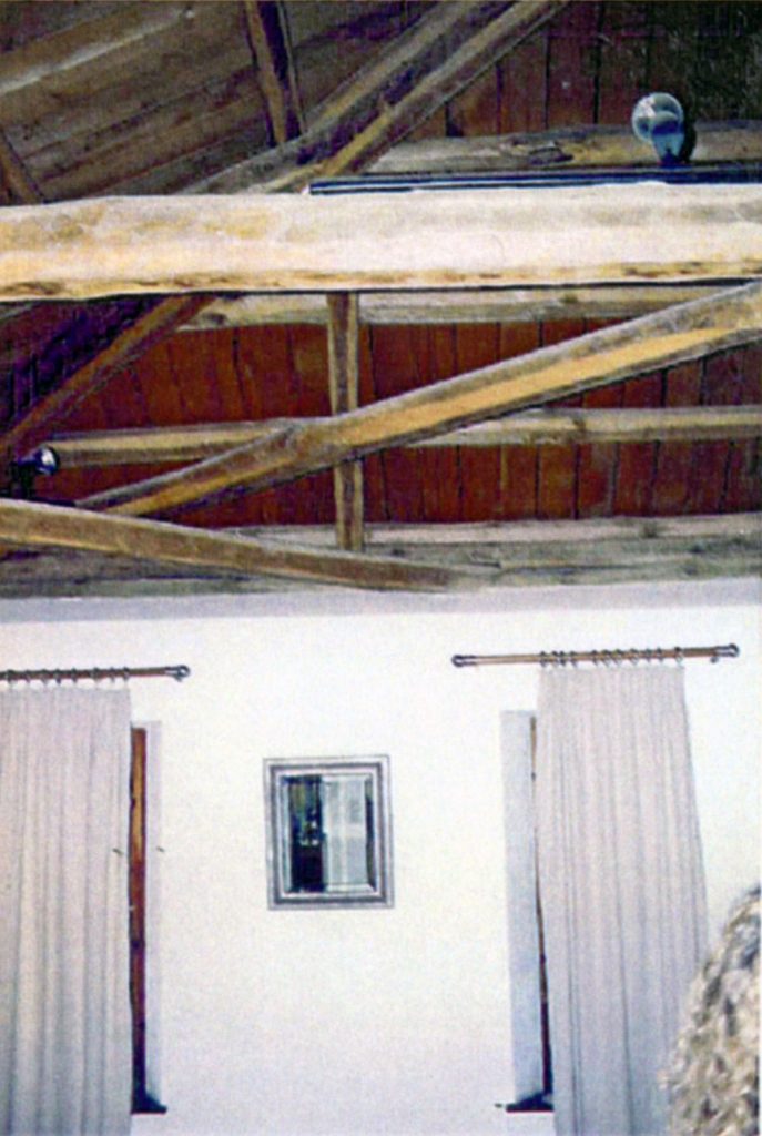 Εσωτερικό δωματίου με ψηλή, ξύλινη οροφή που διαθέτει εκτεθειμένα δοκάρια